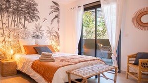 Een slaapkamer met een bed, een bankje, een stoel, een nachtkastje en een muurschildering.