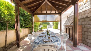 An outdoor patio with a wooden pergola, white plastic chairs, and a table set for dining. - 3010 Appartamento Kalos by Barbarhouse (Melendugno)