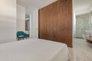 A modern bedroom with a large bed, a teal chair, and a wooden panel wall. - 2306 Attico Elmar by Barbarhouse (Otranto)