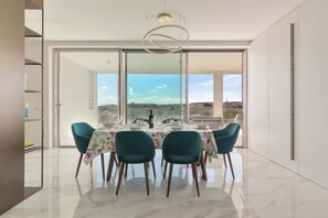 A modern dining area with a table set for four, large windows, and a view of the cityscape. - 2306 Attico Elmar by Barbarhouse (Otranto)