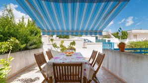 An outdoor patio with a table set for four, surrounded by wooden chairs, under a blue canopy. - 2925 Casa Vacanze di Ivana- Tramontana by Barbarhouse (Santa Cesarea Terme)