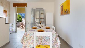 A dining area with a table set for four, a cabinet, and a painting on the wall. - 2925 Casa Vacanze di Ivana- Tramontana by Barbarhouse (Santa Cesarea Terme)