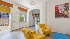 A spacious room with two yellow armchairs, a blue sofa, and a large painting on the wall. - 2925 Casa Vacanze di Ivana- Tramontana by Barbarhouse (Santa Cesarea Terme)