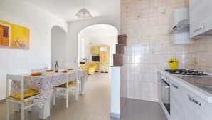 A modern kitchen with white cabinets, a gas stove, and a dining area with a table set for two. - 2925 Casa Vacanze di Ivana- Tramontana by Barbarhouse (Santa Cesarea Terme)