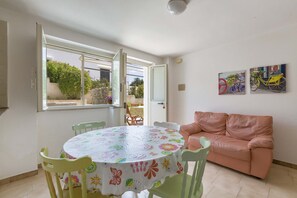 Um quarto com uma mesa redonda coberta por um tecido de mesa floral, um sofá rosa e dois quadros de bicicletas pendurados na parede.