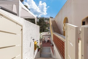 A narrow alleyway with a staircase leading to a building with arched doorways and a tiled floor. - 2328 Mamma Teresa (Castro)