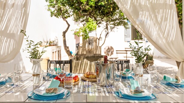 Mesa lista para una comida con vistas a un árbol y un edificio al fondo.