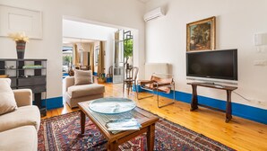 Una sala de estar con sofá, mesa de centro, televisor y vista a otra habitación.