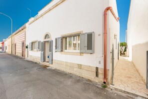 Une rue étroite bordée de bâtiments blancs, un trottoir pavé et un ciel d’un bleu limpide.
