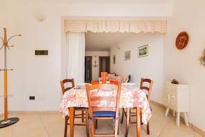 Un coin repas avec une table dressée pour quatre personnes, des chaises, un porte-manteau et un meuble.