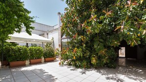 A courtyard with tiled flooring, potted plants, and a white umbrella structure. - 3005 Dimora Donn`anna - Mono 1 by Barbarhouse (Ortelle)