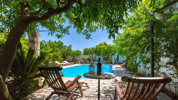 A pool area with wooden chairs and a table, surrounded by greenery and a stone pathway. - 3005 Dimora Donn`anna - Mono 1 by Barbarhouse (Ortelle)