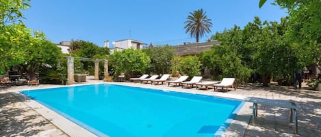A rectangular swimming pool with a clear blue water surface, surrounded by a stone deck.