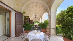 An outdoor patio with a round table set for dining, surrounded by potted plants and a stone archway. - 3005 Dimora Donn`anna - Mono 1 by Barbarhouse (Ortelle)