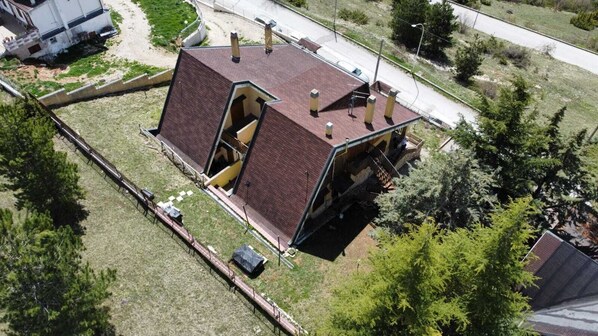 An aerial view of a house with a unique architectural design, featuring a large open doorway and multiple chimneys.