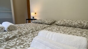 Un letto rifatto con cura, copriletto decorato, una lampada da comodino e due stampe di animali appese alle pareti.