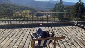 Una persona seduta su una panchina con vista su un paesaggio montuoso.