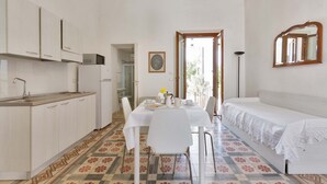 A compact room with a kitchenette, a dining table with chairs, a sofa, and a patterned floor. - 3008 Dimora Donn`anna - Bilo 4 by Barbarhouse (Ortelle)