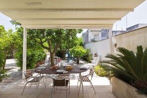 An outdoor patio with a round table set for dining, surrounded by chairs, under a white pergola. - 3008 Dimora Donn`anna - Bilo 4 by Barbarhouse (Ortelle)