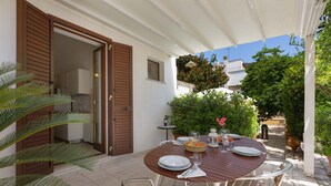 An outdoor dining area with a round table set for two, surrounded by potted plants and a white pergola. - 3008 Dimora Donn`anna - Bilo 4 by Barbarhouse (Ortelle)