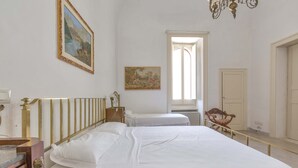 Un dormitorio con dos camas, un aparador de madera, una araña y un cuadro en la pared.