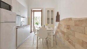Una cocina estrecha con armarios blancos, un refrigerador y una zona de comedor con mesa y sillas.