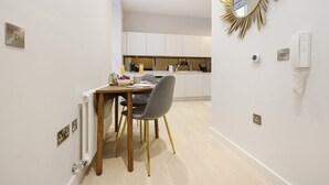 A modern kitchen with white cabinets, a dining table with chairs, and a gold-framed mirror on the wall.