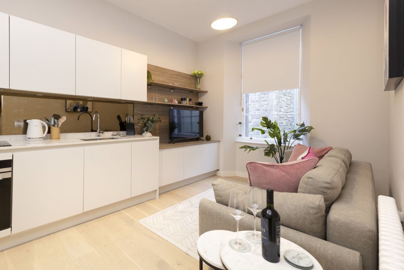A modern kitchen with white cabinets, a built-in oven, and a window.