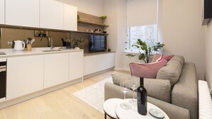 A modern kitchen with white cabinets, a built-in oven, and a window.
