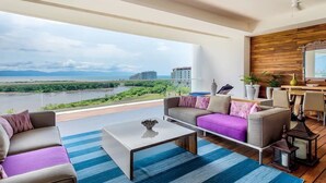 Un balcón amplio con vistas a un río y edificios, amueblado con un sofá, una mesa de centro y elementos decorativos.