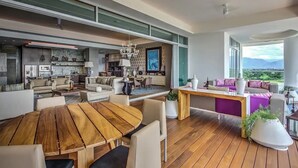 Un amplio espacio de sala con una mesa de comedor de madera, sofás y un ventanal con vistas al exterior.
