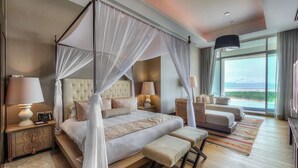 Amplia habitación con cama con dosel, un sofá y vistas al exterior.