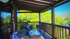 Un espace extérieur aménagé, abrité et doté de mobilier en osier et d’une table, offrant une vue sur un paysage verdoyant et luxuriant.