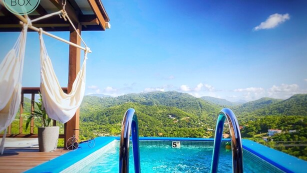 Une piscine dont la profondeur maximale est indiquée à 1,5 mètre, entourée d’une terrasse en bois et agrémentée d’un hamac.