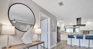 A modern kitchen with a central island, bar stools, and a large mirror.