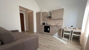 Un salon moderne avec un canapé, une cuisine dotée de meubles en bois et un coin repas comprenant une table et des chaises.