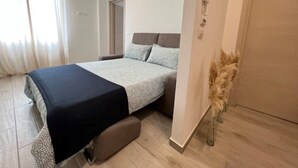 Une chambre à coucher avec un lit, une table de chevet, une porte et une fenêtre avec des rideaux.