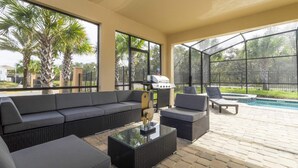 Eine Terrasse im Freien mit einer Eckcouch, einem Couchtisch und einem Poolbereich.