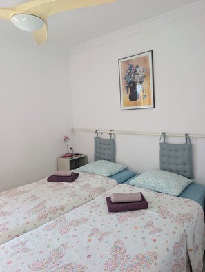 A bedroom with two beds, a nightstand, a lamp, and a framed floral artwork on the wall. - Algarrobo Costa luxury apartment POMELO , seafront, 6 pers, pool, sandy beach (Algarrobo)