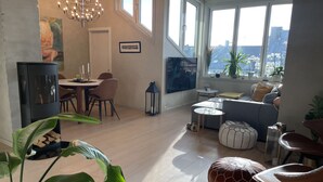 A modern living room with a dining area, large windows, and a staircase leading to an upper level. - Exclusive & Elegant Frogner Apartment in the Heart of Oslo (Oslo)