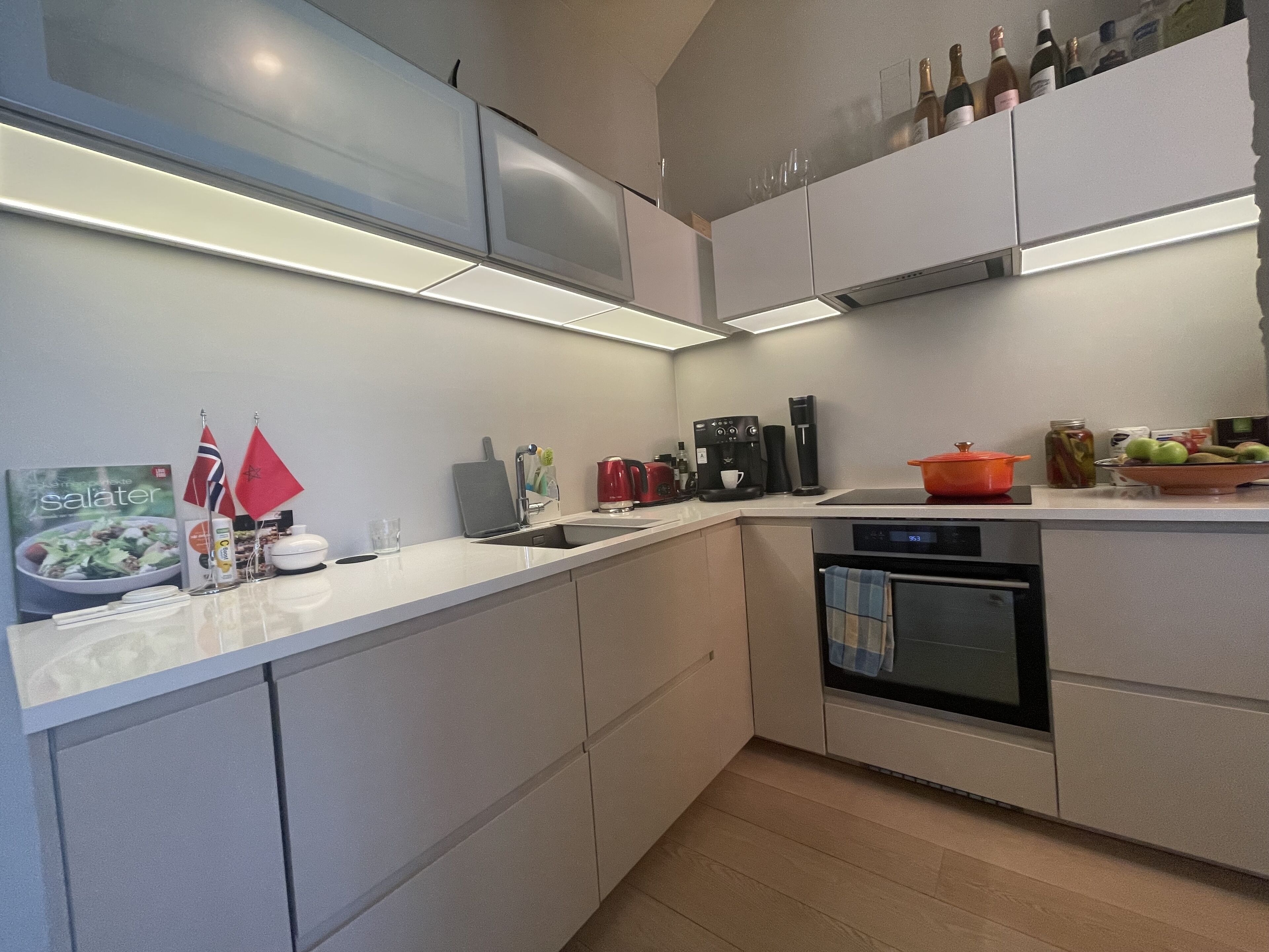 Una cocina moderna con horno empotrado, cafetera y diversos utensilios de cocina.