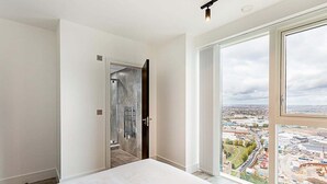 Ein Schlafzimmer mit großem Fenster und Blick auf die Stadt.