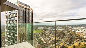 Ein Hochhaus mit moderner Glasfassade und Blick auf eine Stadtlandschaft mit Wohngebieten und Straßen.
