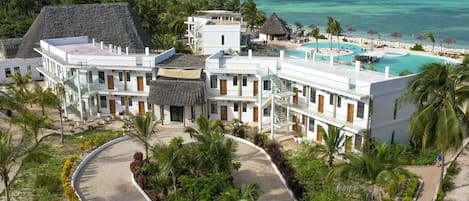 A resort with a pool, palm trees, and a view of the ocean.
