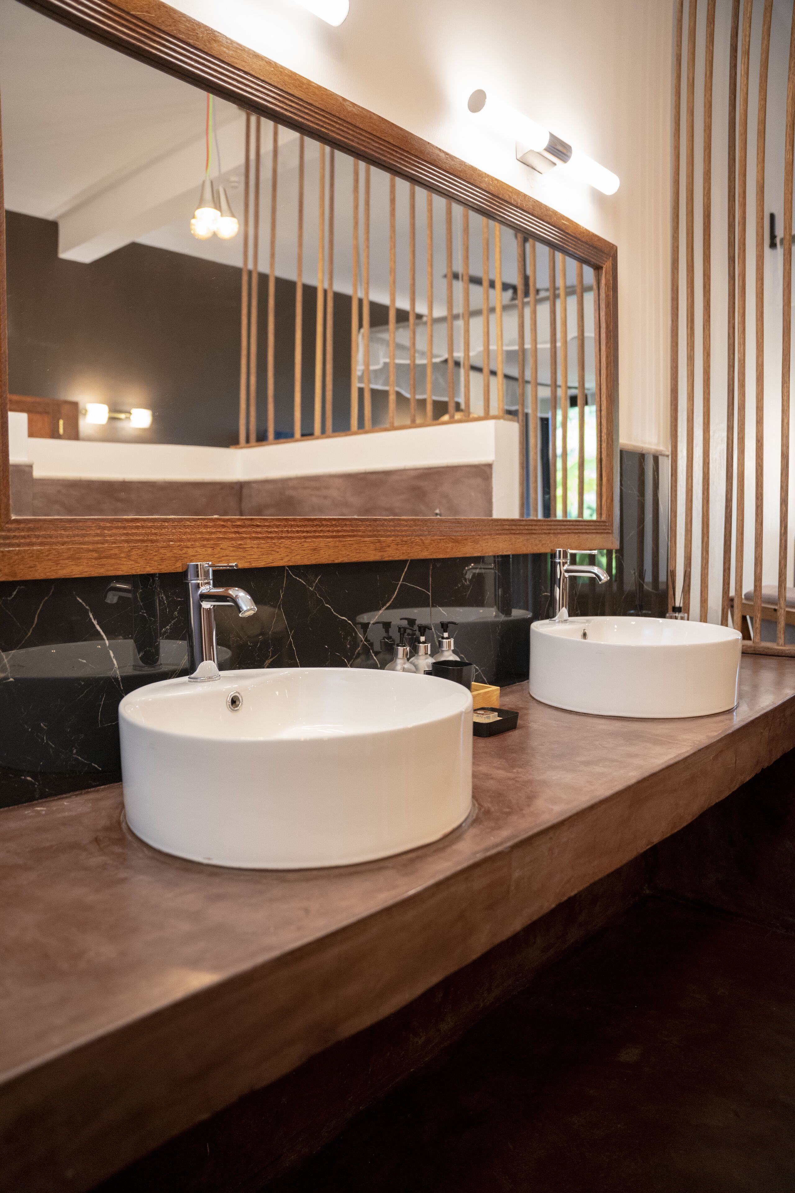 Un baño con dos lavamanos redondos, un espejo grande y paneles de madera.