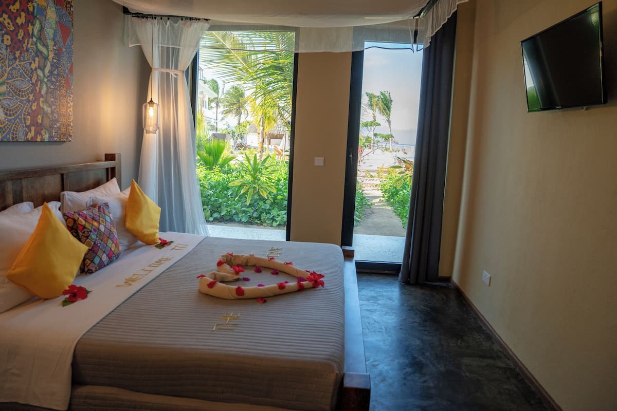 A hotel room with a bed, pillows, a TV, and a view of the outdoors.