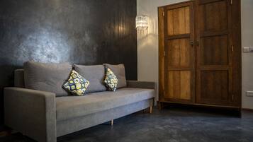 Una sala de estar moderna con un sofá gris, cojines estampados, un armario de madera y una pared con textura.