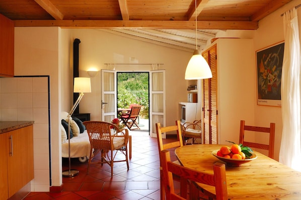 A cozy kitchen with a dining area, wooden furniture, and a view of greenery outside.