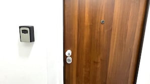 Une porte en bois fermée, avec une serrure et un bouton de sonnette fixés sur le mur à côté.