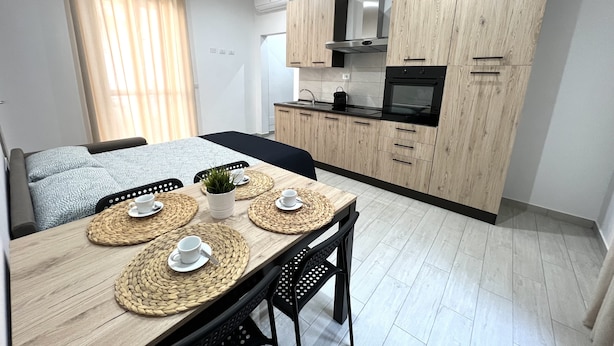 Une cuisine moderne avec des meubles en bois, un four encastré et un plan de travail noir.